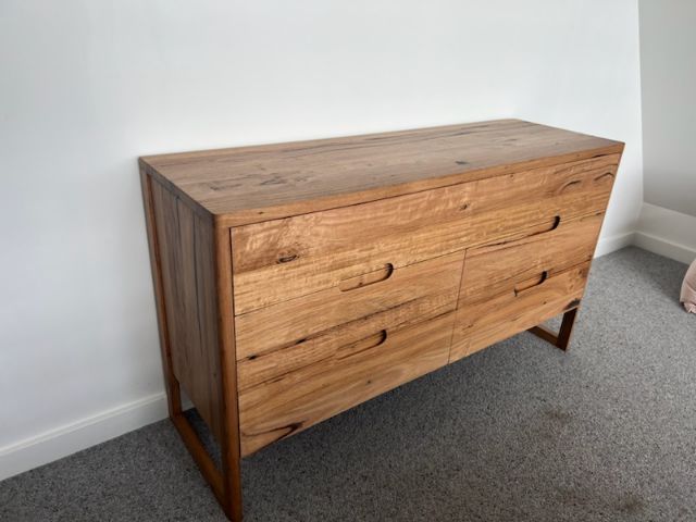Contemporary timber dresser with natural finish and integrated handles.