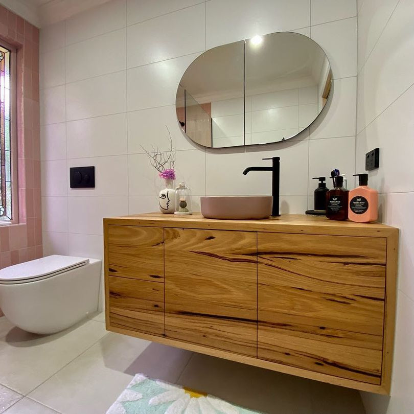 Custom bathroom vanity crafted from recycled hardwood featuring a vessel basin, round mirror, and modern matte black tapware.