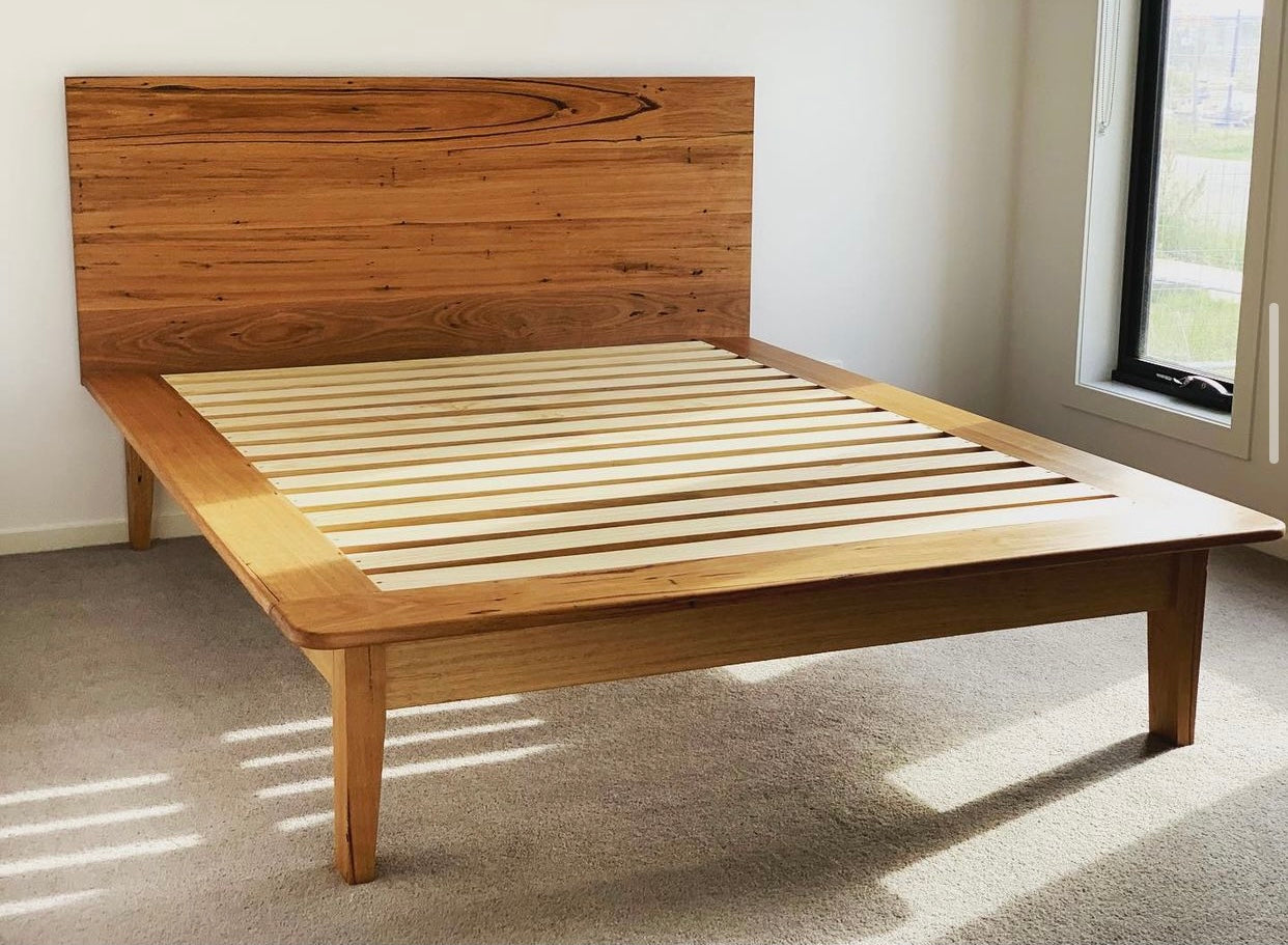 Queen-sized timber bed frame with slatted base and statement headboard.