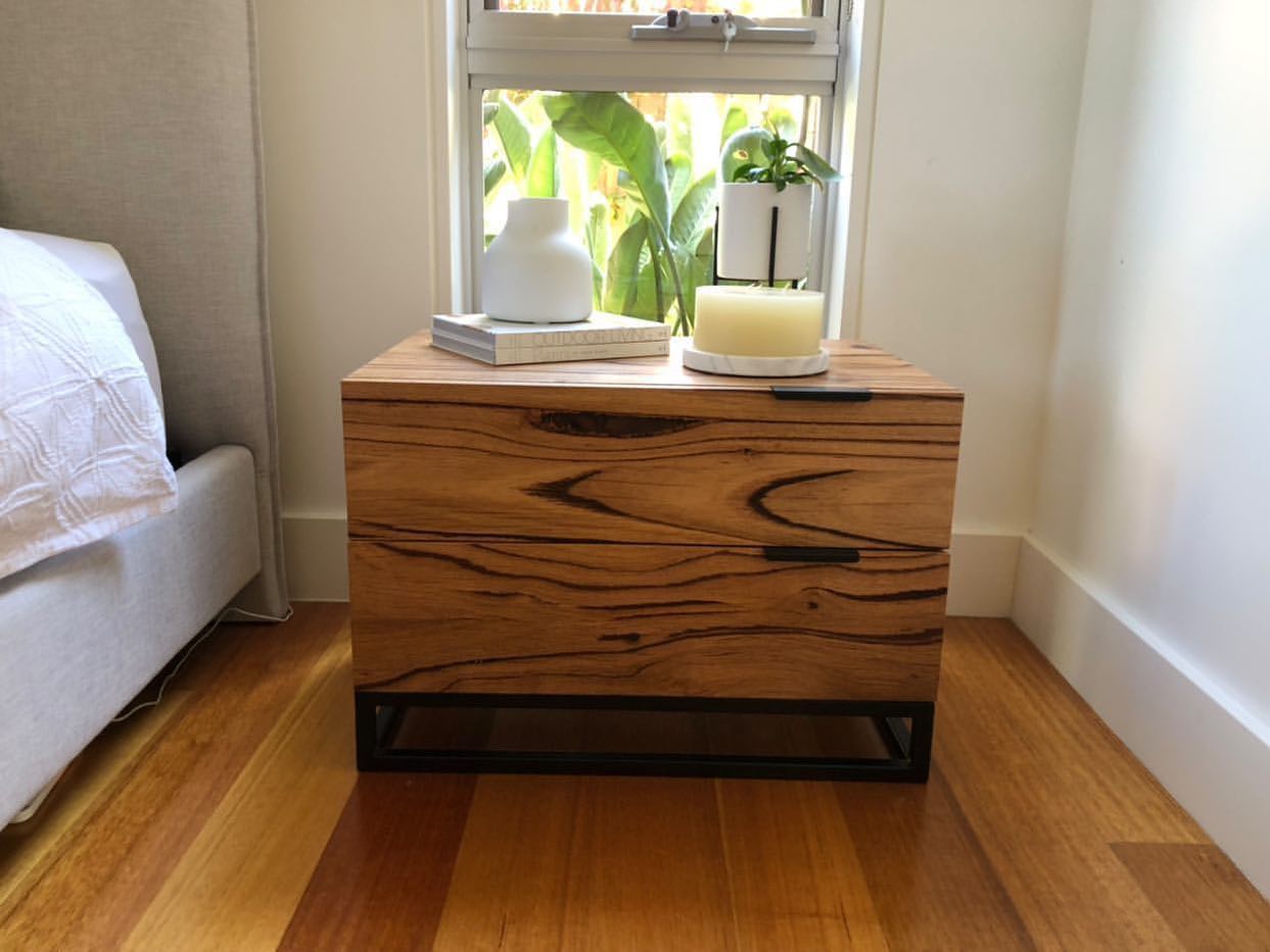 Modern solid timber bedside table with black steel base and soft-close drawers.
