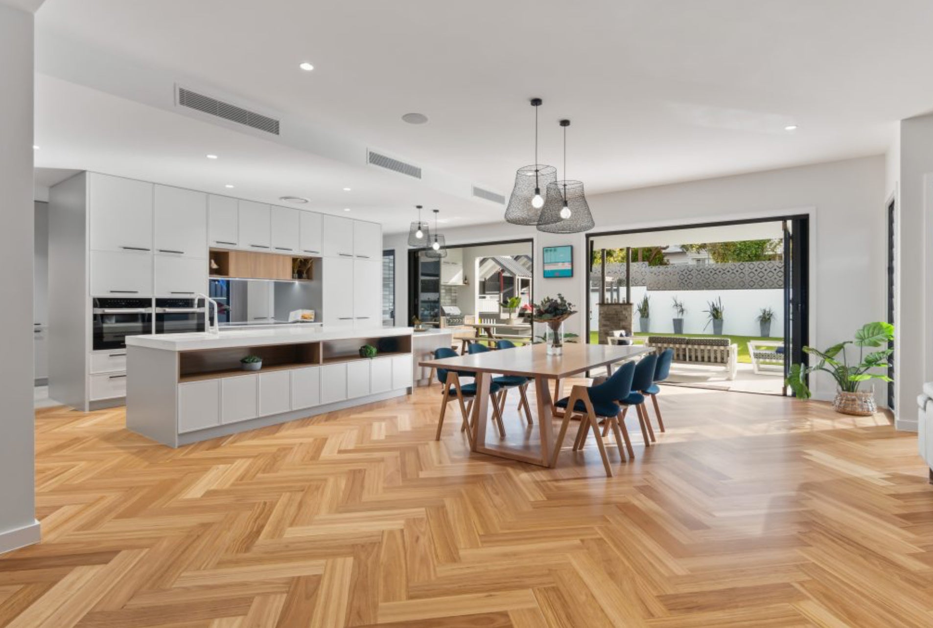 Recycled engineered herringbone flooring laid in a bright contemporary kitchen and dining area