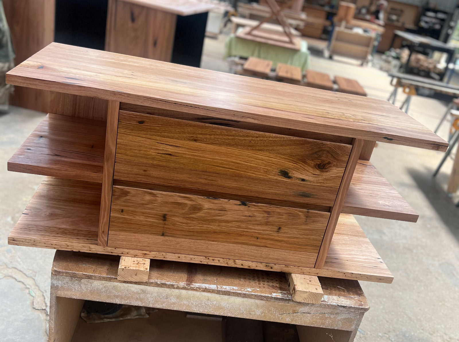 Custom Falcon floating vanity made from solid reclaimed timber, featuring open side shelving and seamless drawer fronts in a natural matte finish.