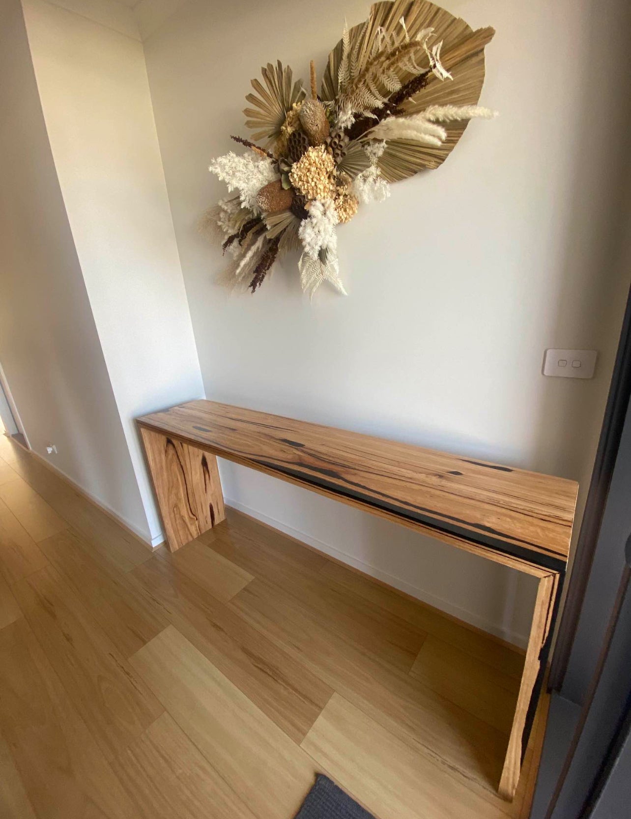 Sleek hallway console made from natural spotted gum timber with black detail strip, slim and modern profile.